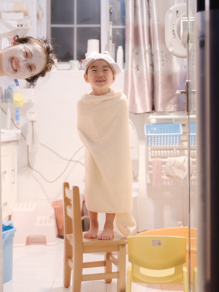 浴室里，母亲俯身照顾年幼的孩子